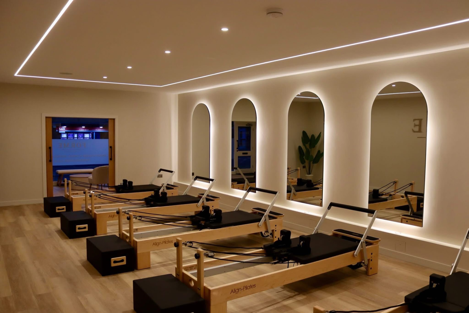 Five pale wood reformers in a sunlit boutique pilates studio